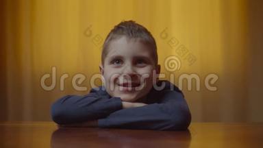 自闭症男孩坐在办公桌前表现情绪的肖像。 有自闭症的孩子在家笑。 自闭症意识